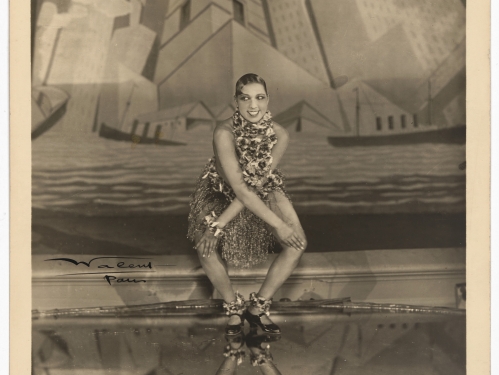 Sepia-toned picture of woman smiling, dancing on a stage with hands on opposite knees.