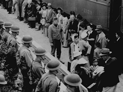 Black and white photograph of people standing in front of train.