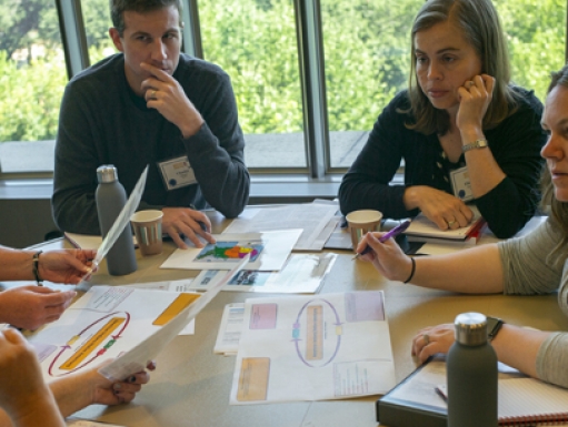 A group of educators deliberate a printout around a table.