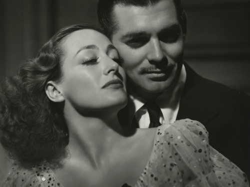 A man embraces a woman from behind in a black and white image.